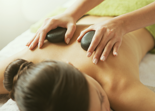 Kvinna som får massage med varma lavastenar